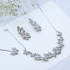 Silver butterfly necklace and earrings on a white surface with dried flowers.