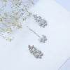 Silver bow-shaped earrings on a light surface with dried flowers.
