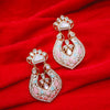 Ornate earrings with pink and gold details on a red fabric background