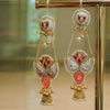 Ornate earrings with gold, red, and pearl details on a reflective surface.