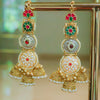 Ornate gold earrings with red and green gemstones on a stand.