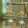 Ornate gold and silver earrings with red stones on a stand.