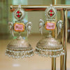 Ornate earrings with pink gemstones and pearl details on a stand.