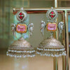 Ornate earrings with pink gemstones and pearl details on a stand.