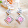 Pair of earrings with pink gemstones and silver accents on a beige fabric background.