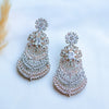 Pair of ornate earrings with clear gemstones on a light background